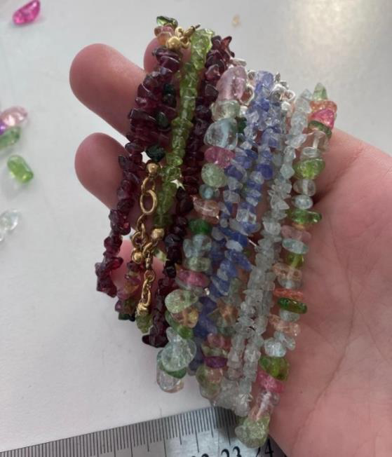 Bundle of gemstone chip bracelets held above a measuring ruler