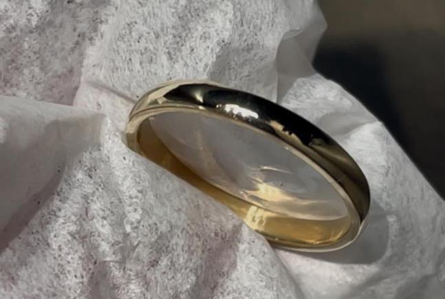 Gold-plated silver wedding band laid on a white cloth