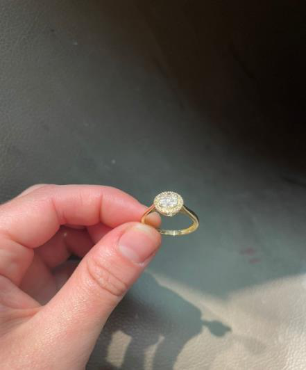 Before resizing, a gold ring with a crown setting held in a finger